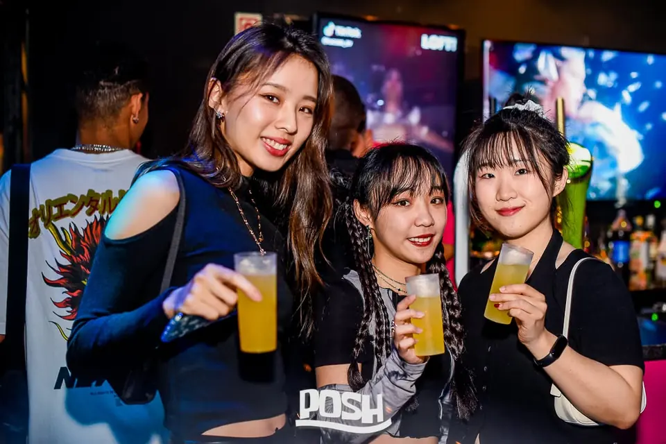 Três amigas com bebidas junto ao bar